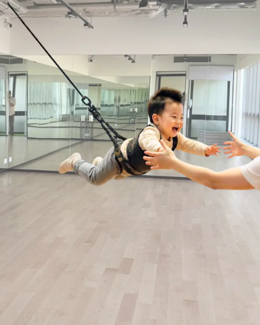 A child suspended in a bungee harness mid flight during a class at MosKiddo