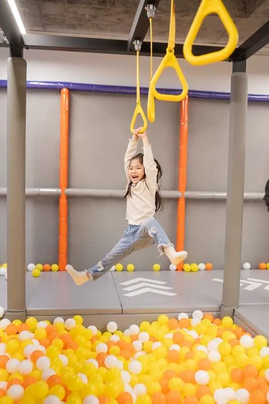 A child swinging from gymnastic rings above the ball pit at MosKiddo